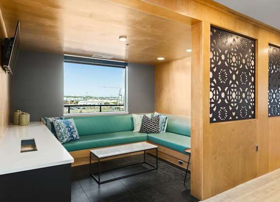 A room with a green couch and a television on the wall.