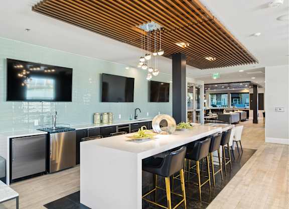 A modern kitchen with a white island and black bar stools.