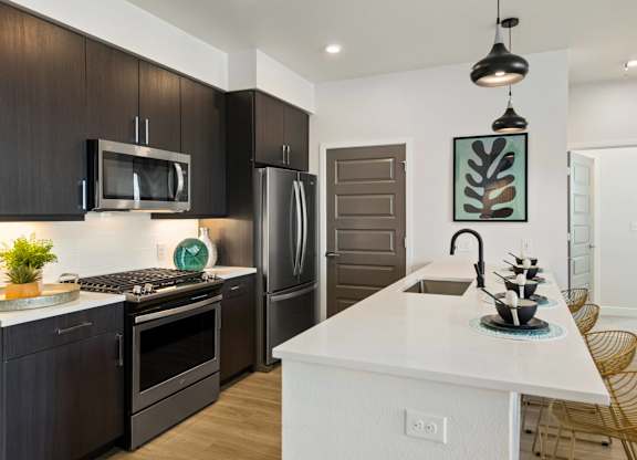 A modern kitchen with dark brown cabinets and a white island.
