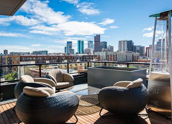 A balcony with chairs and a city skyline in the background.