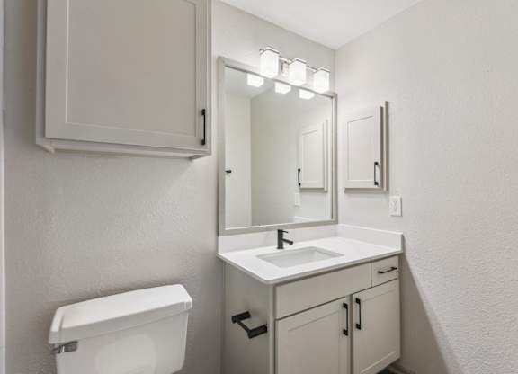 A white bathroom with a toilet, sink, and mirror.