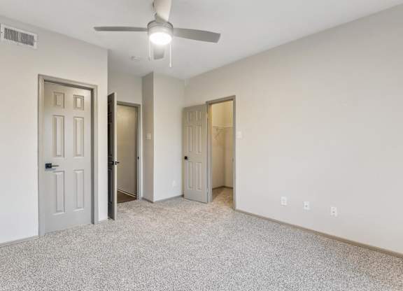 A room with a ceiling fan and three doors.