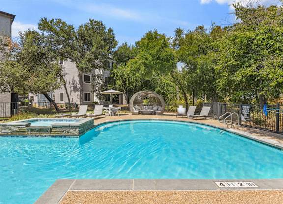 A swimming pool surrounded by trees and chairs.