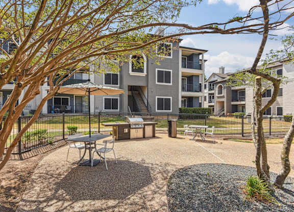 A courtyard with a picnic table surrounded by trees and apartment buildings.