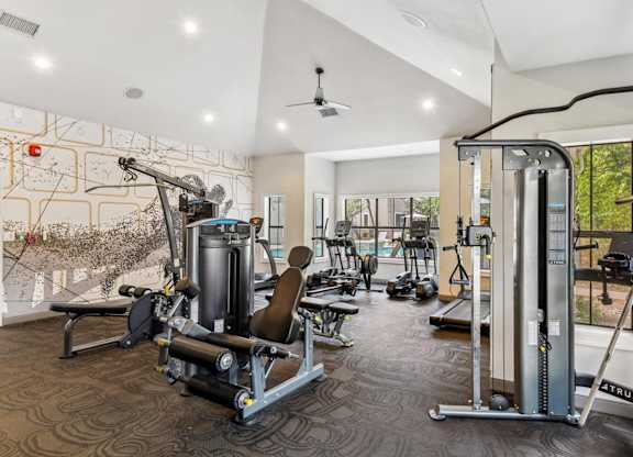 A gym with a variety of equipment including a weight bench, a leg press machine, and a cable machine.
