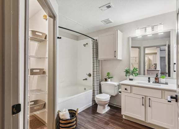 A bathroom with a toilet, sink, and mirror.