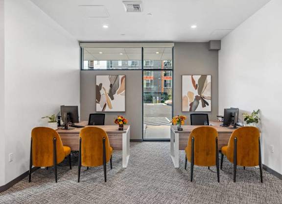 A room with a desk and chairs with a painting on the wall.