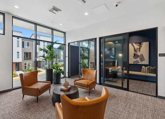 A modern living room with brown chairs and a glass door.