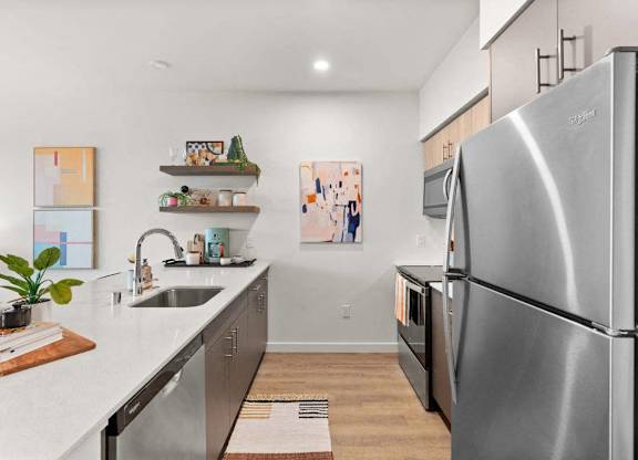 A modern kitchen with a stainless steel refrigerator and a sink with a plant on the counter.