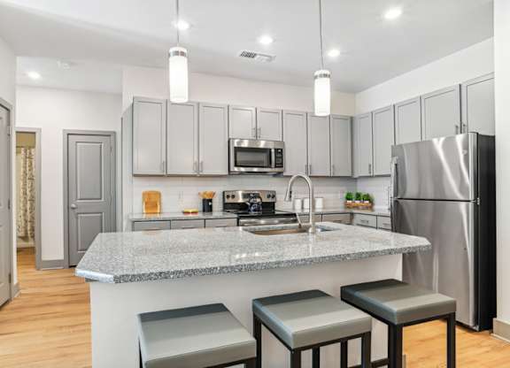 A kitchen with a granite countertop and stainless steel appliances.