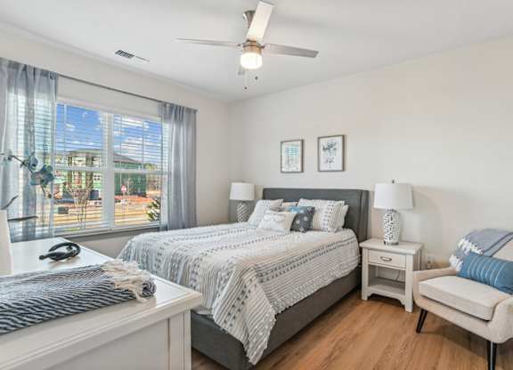 A bedroom with a large bed, a chair, and a ceiling fan.