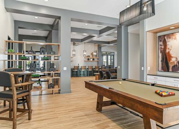 A billiard table is in the middle of a room with a bar area.