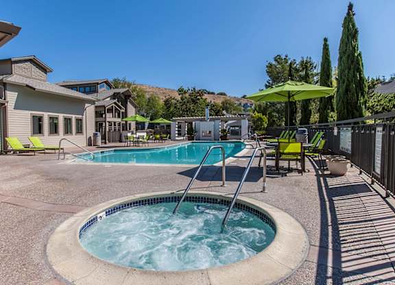 our resort style hot tub is surrounded by patio furniture and a pool