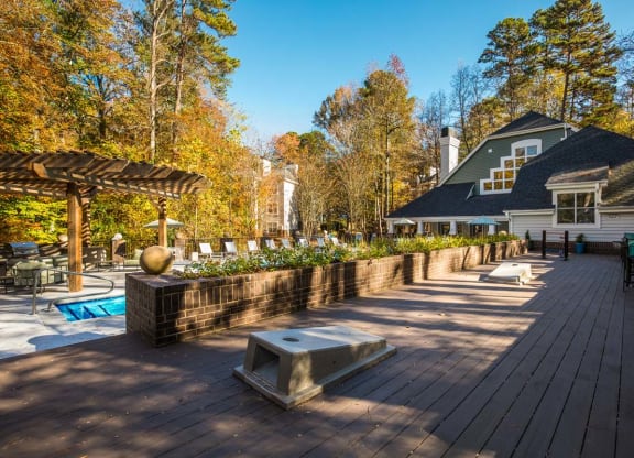 a large deck with a pool and a house in the background