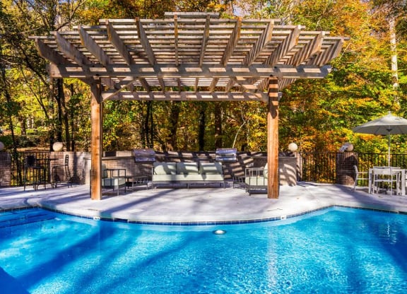 a swimming pool with a wooden pergola next to it