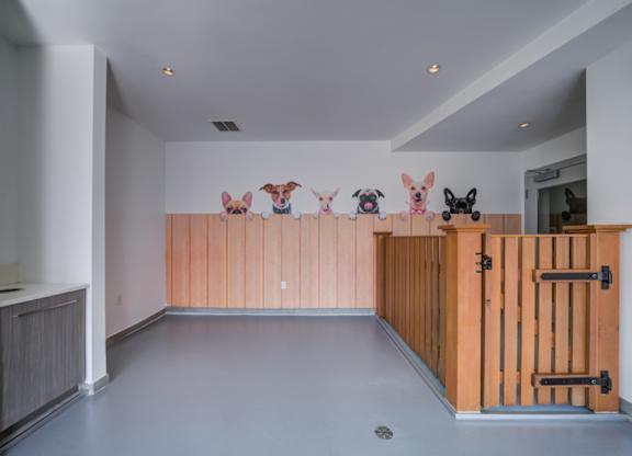 A room with a grey floor and a wooden partition with drawings of dogs on it.