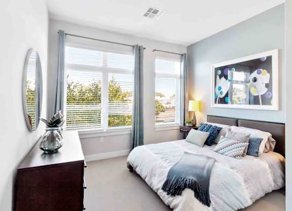 A bedroom with a large bed and a window with blinds.