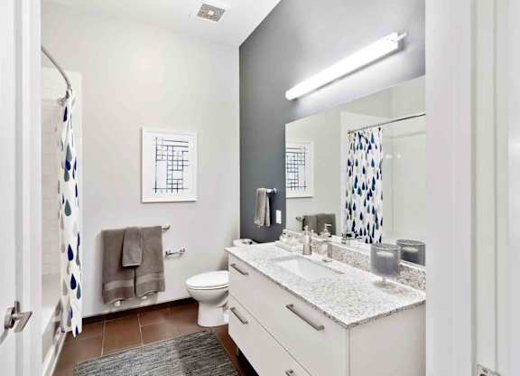 A bathroom with a toilet, sink, mirror, and a shower curtain.