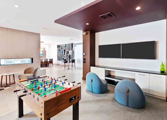A foosball table is in the middle of a room with a TV and bean bag chairs.