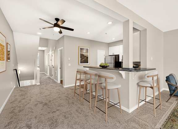 A spacious kitchen and bar area with a ceiling fan and lighting.