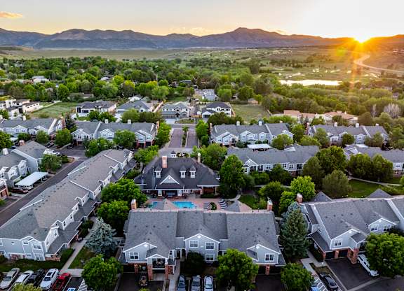 A sunset view of a residential neighborhood with houses and parked cars.