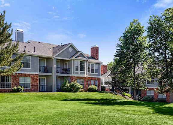 A large, well-maintained apartment complex with a green lawn in front.