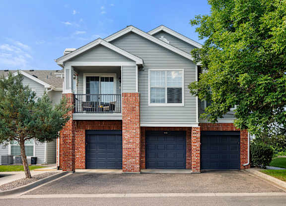 A grey house with a balcony and two garages.