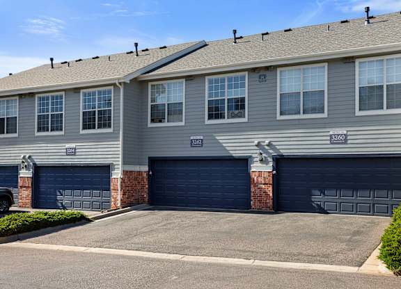 A grey building with two garages and a brick pillar.