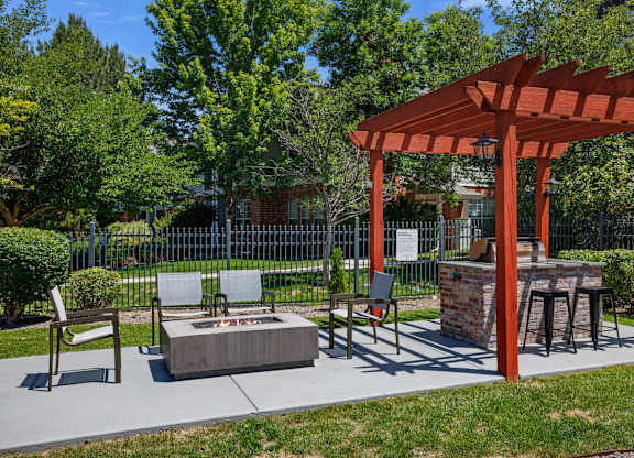 A park with a fire pit and a pergola.