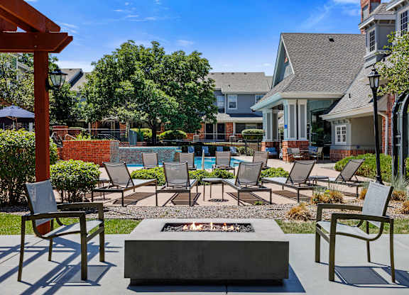 A patio with a fire pit and chairs.