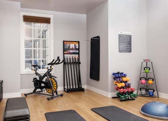 A home gym with a stationary bike, weights, and exercise equipment.