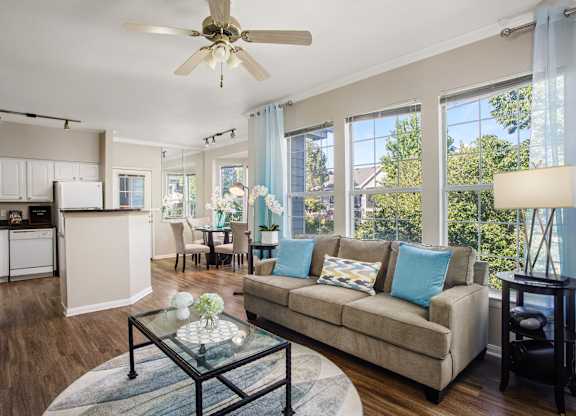 A living room with a couch, a glass coffee table, and a ceiling fan.