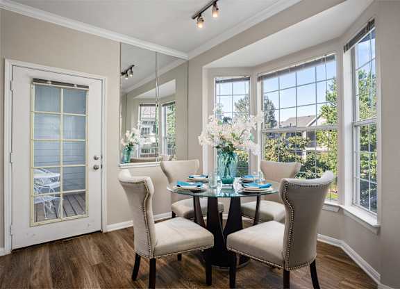 A dining room with a table set for two and a view of the backyard.