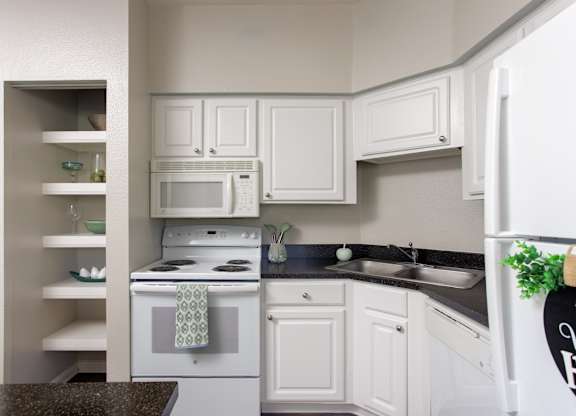 A kitchen with white cabinets and a black countertop.