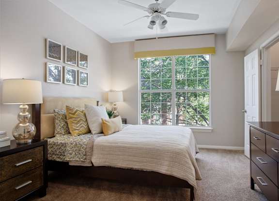A bedroom with a bed, dresser, and ceiling fan.