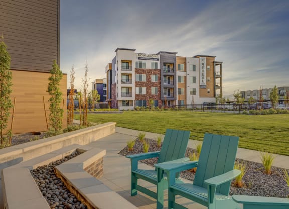two green chairs on a patio with an apartment building in the background