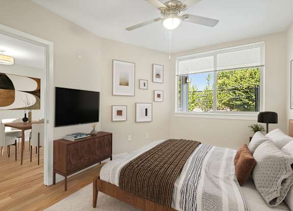 A bedroom with a bed, a television, and a ceiling fan.