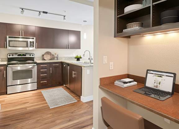 A laptop is open on a desk in a kitchen.