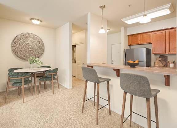 A kitchen area with a bar and chairs.