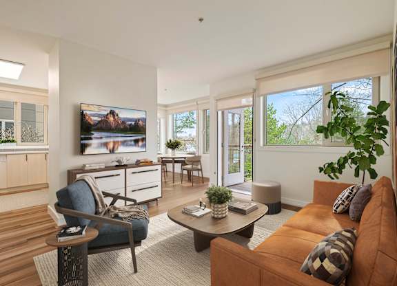 A living room with a brown couch and a TV mounted on the wall.