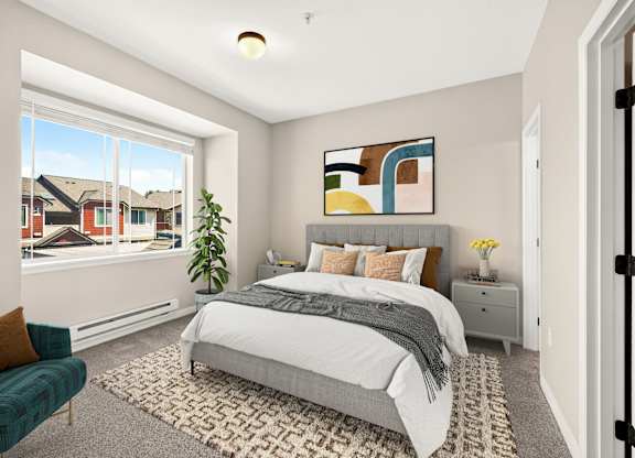 A bedroom with a large bed, a green chair, and a painting on the wall.