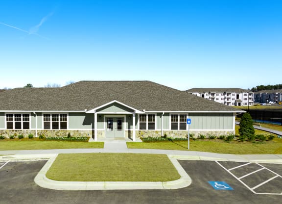 the front of a building with a parking lot and grass