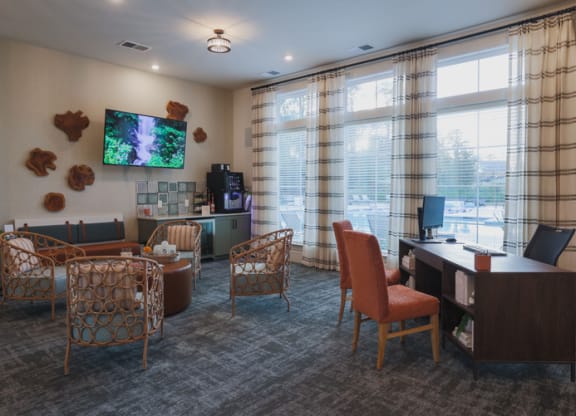 a room with chairs and a desk with a tv on the wall