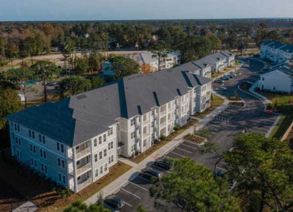an aerial view of a large apartment complex with a parking lot and trees