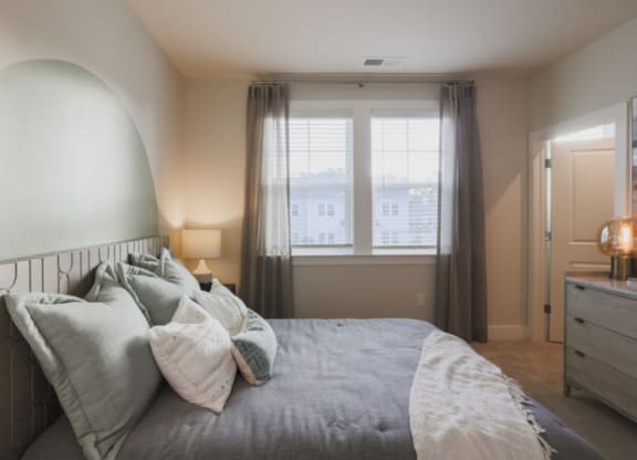 a bedroom with a bed and a dresser in front of a window