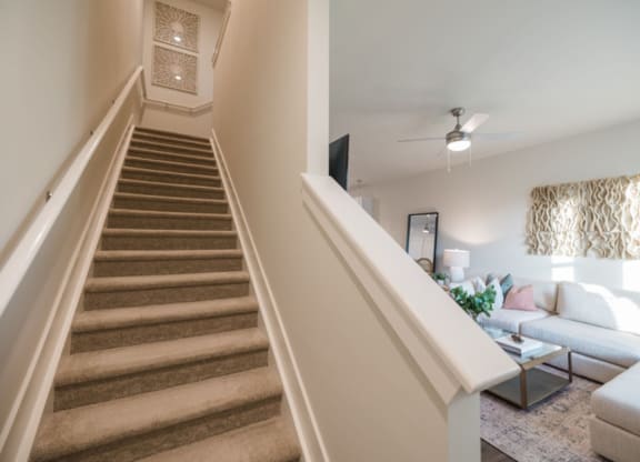 a view from the bottom of the stairs looking up at the living room with a couch and
