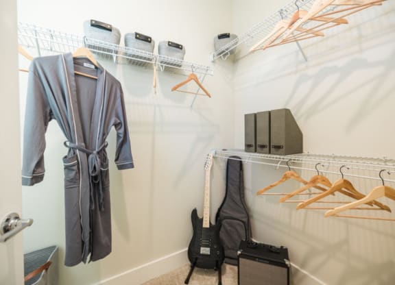 a walk in closet with a guitar and hangers