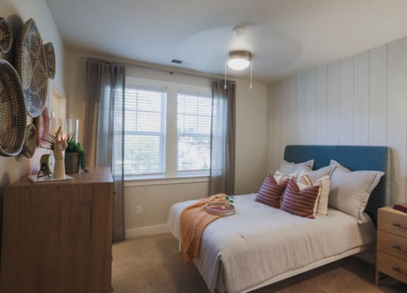 a bedroom with a bed and a dresser in front of a window