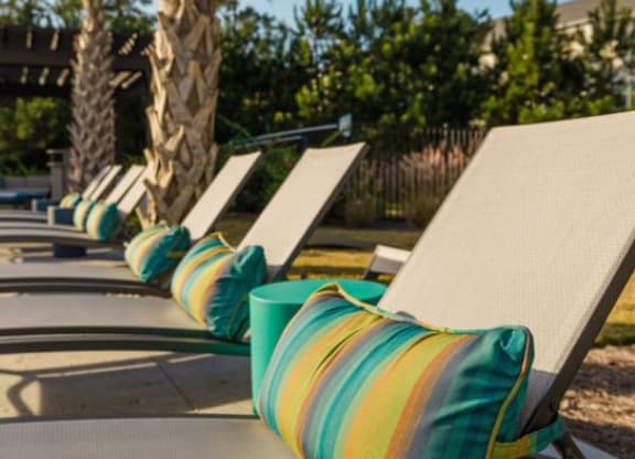 a row of lawn chairs sitting on top of a sandy beach