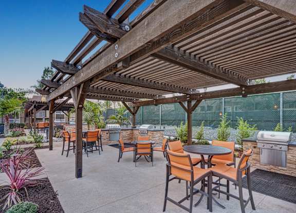 A patio with tables and chairs under a wooden pergola.